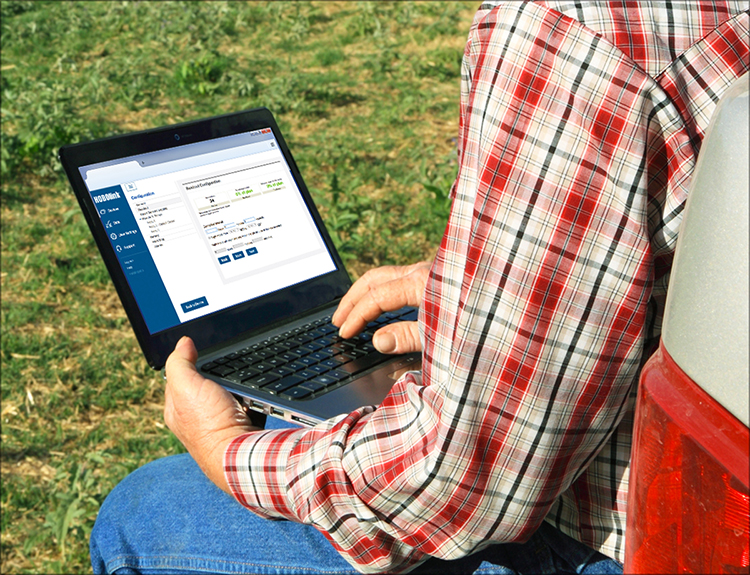 Laptop rests on researcher's lap who sits outside while configuring HOBOlink software, which is visible on the screen