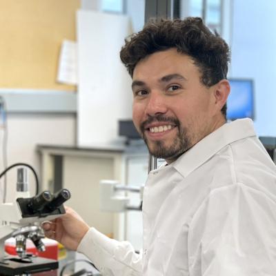 Matt Aguayo in the lab sitting with a microscope
