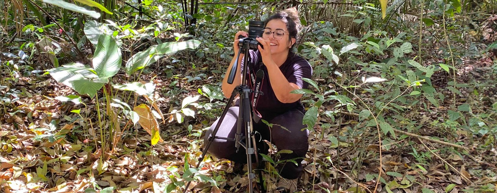 Gabriella de Souza in woods photographing plants