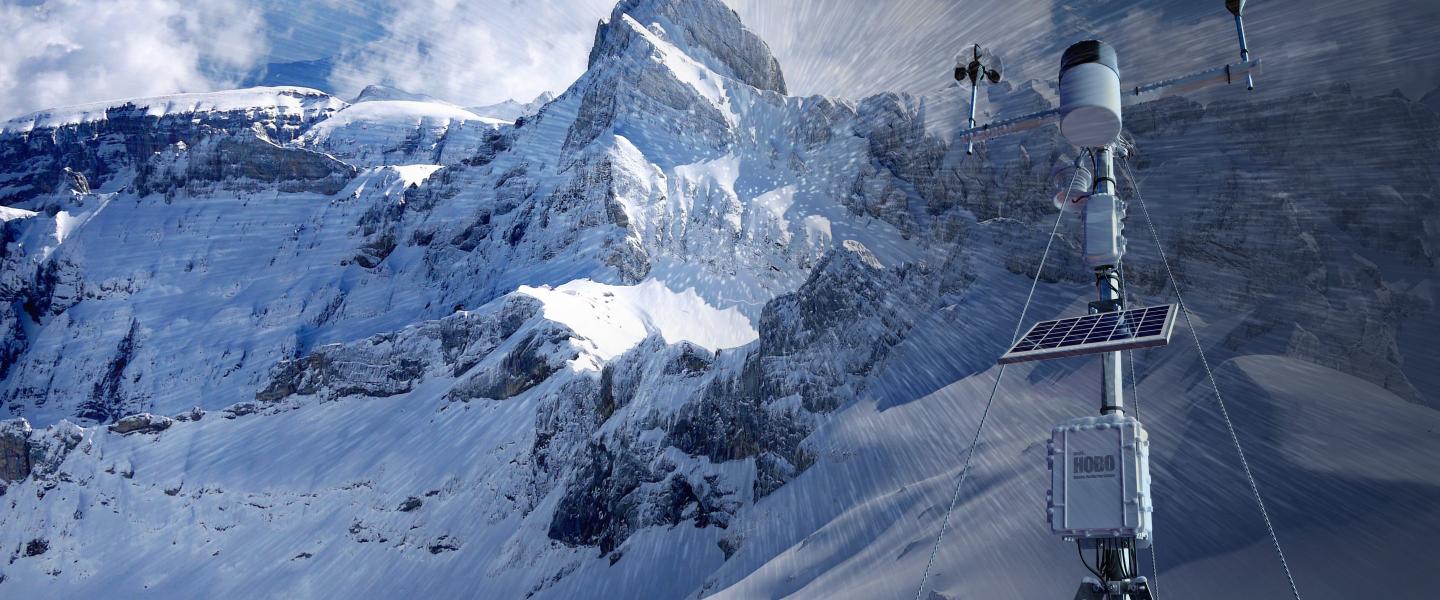 Onset's HOBOnet RX3000 Weather Station against an Alpine mountain in rugged, snowy conditions