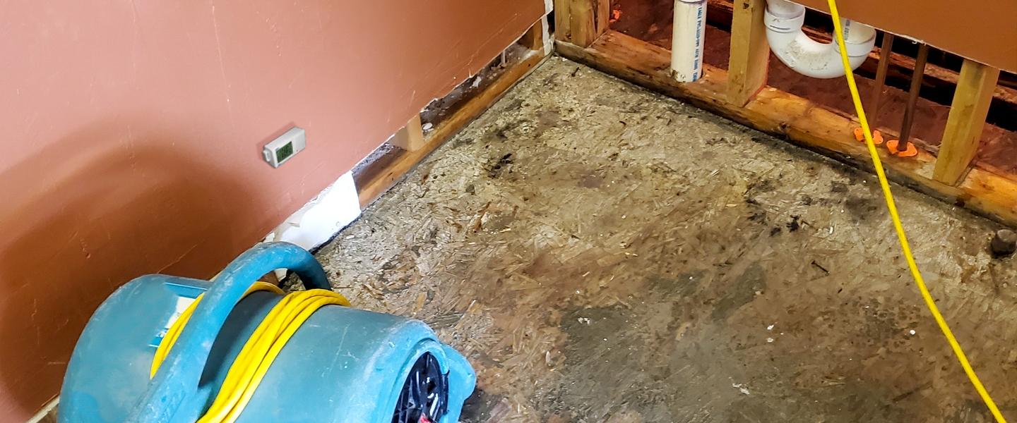 Fan on floor drying out damaged property with HOBO logger deployed on wall