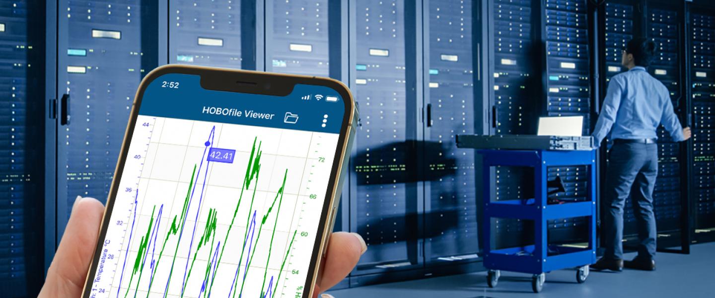 Phone in hand with app monitoring conditions in data center server room