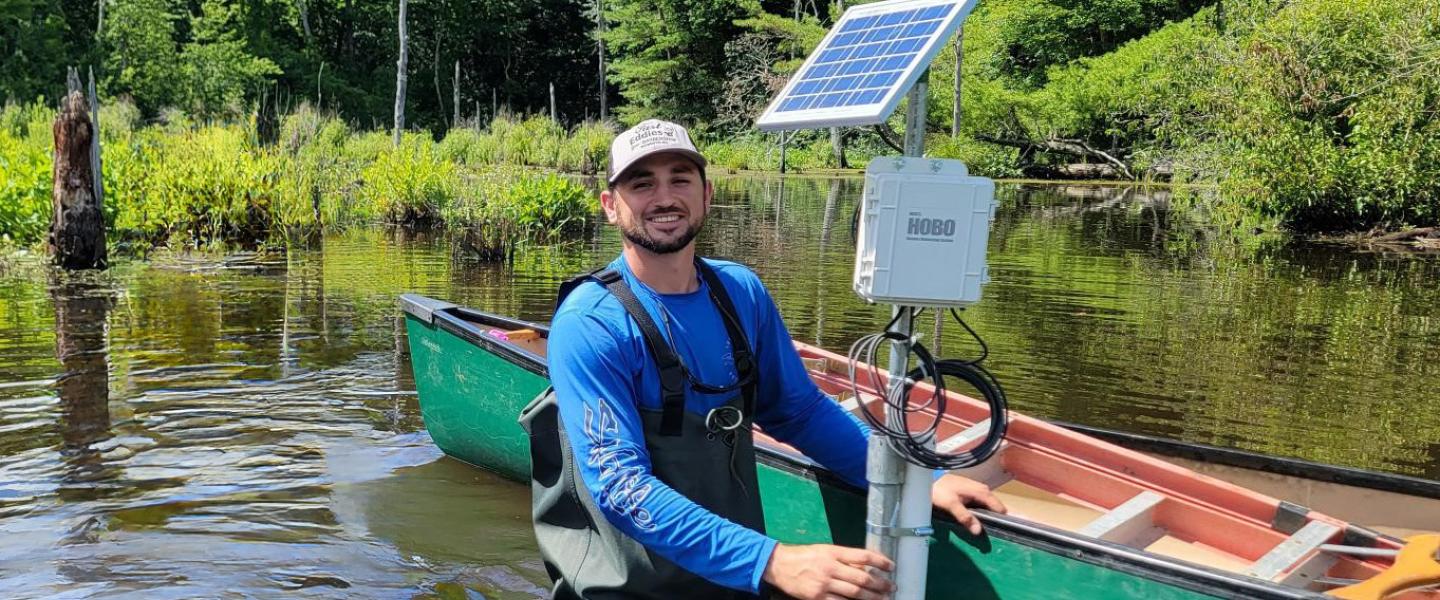 HOBO expert in waders in wetland with remote monitoring station that measures water level