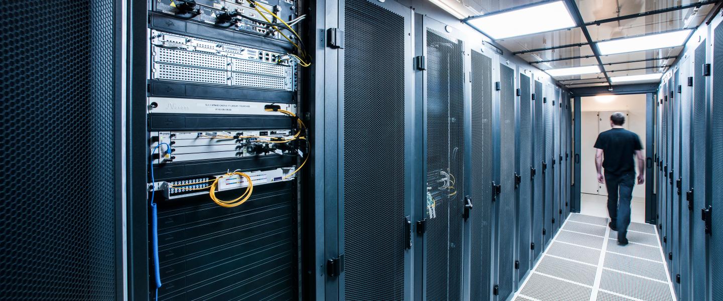 man walking along server room rack aisle