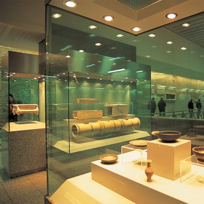A view from inside a museum with glass paneled displays showcasing various earthenware antiquities.