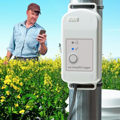 remote data logger in farmer's field with farmer checking crop monitoring data with mobile phone