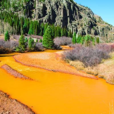 River runs red with mine tailings, severely impacting the aquatic ecosystem.