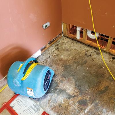 Fan on floor drying out damaged property with HOBO logger deployed on wall