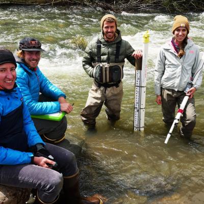 Researchers in river holding water monitoring data loggers