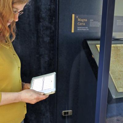 Woman observing the Magna Carta exhibit with iPad